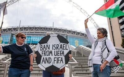 Pro-Palestinian activists protest with a football-shaped sign and a Palestinian flag outside Wembley Stadium to demand that the Football Association issue a public statement calling for the Israeli Football Association (IFA) to be suspended from participation in UEFA and FIFA tournaments, on October 2, 2025 in London, United Kingdom. (Mark Kerrison/In Pictures via Getty Images via JTA)